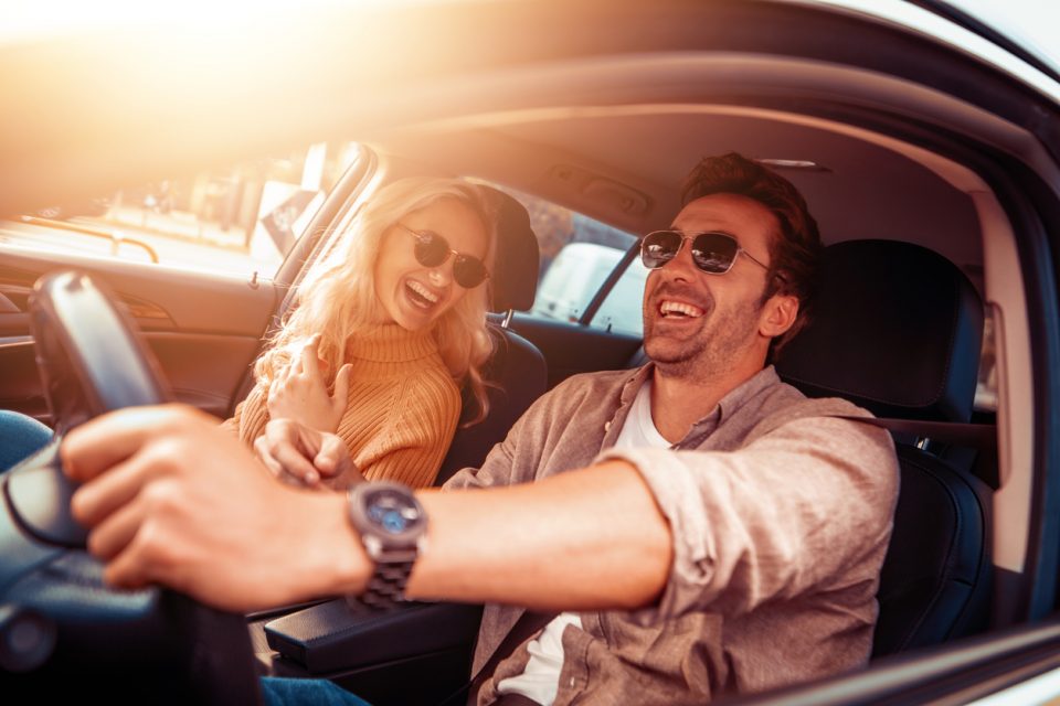 Happy young couple enjoying a long drive in a car.