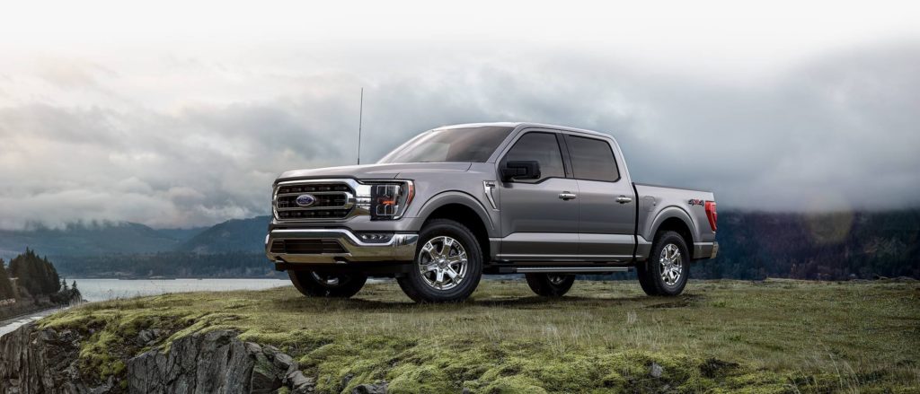 silver truck on grassy hill with cloudy background