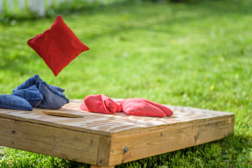 Bag flying onto corn hole board in backyard