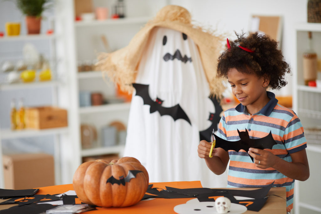 Young boy cutting out a bat from construction paper to make Halloween decorations