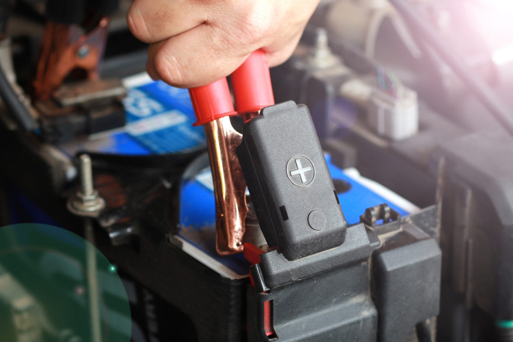 close of up jumper cables connected to dead car battery