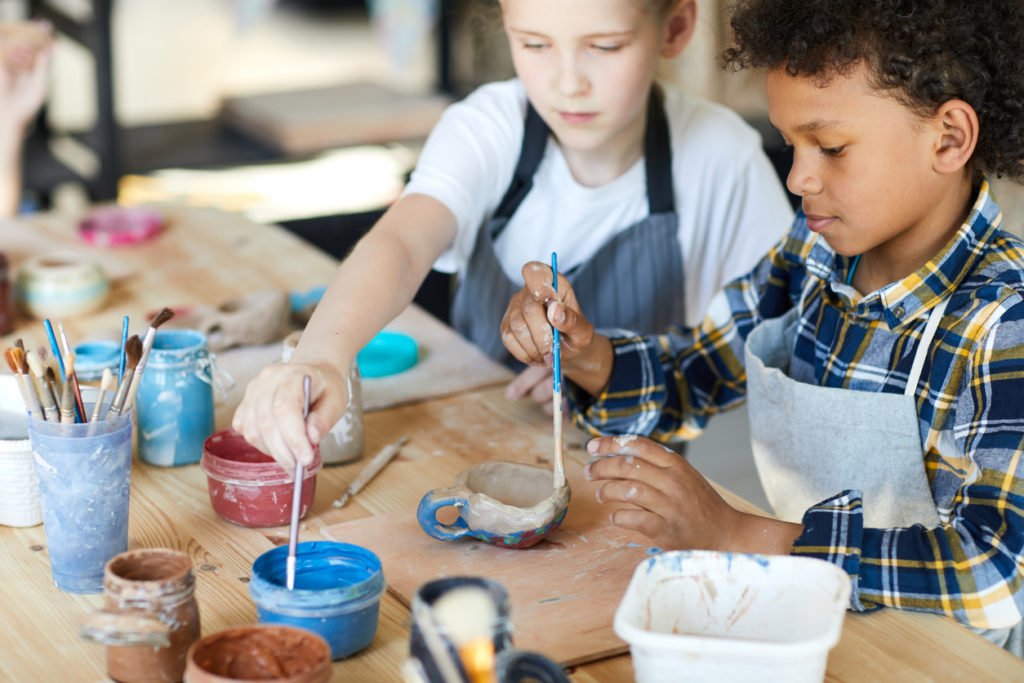 kids painting clay cup