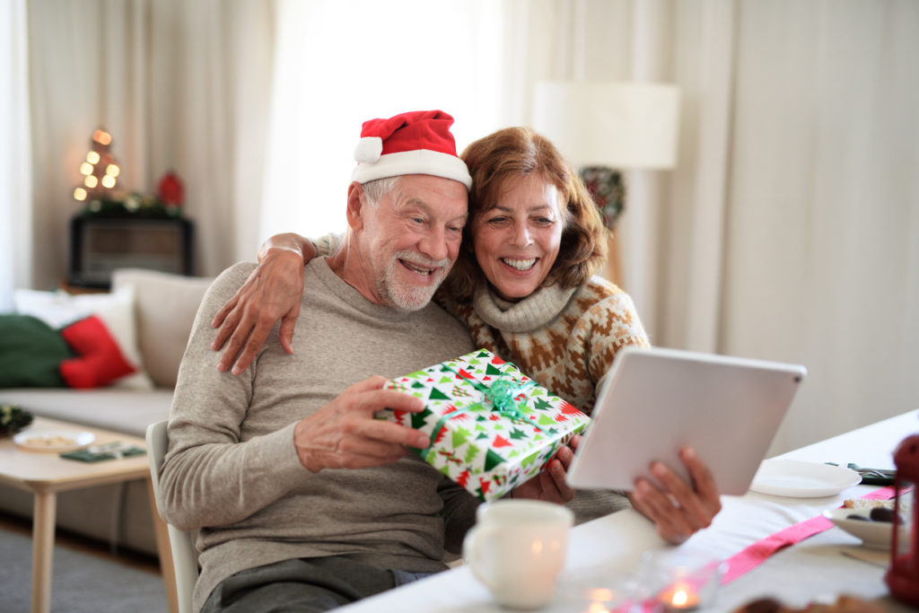 Front view of senior couple indoors at home at Christmas, having video call with family.