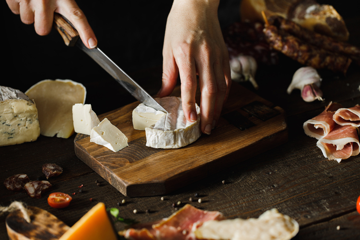 hand cutting cheese on wooden board